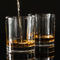 Set of two clear whiskey glasses on a dark wooden surface