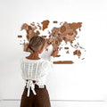 3D wooden world map in natural oak brown and tan tones displayed on a modern living room wall.