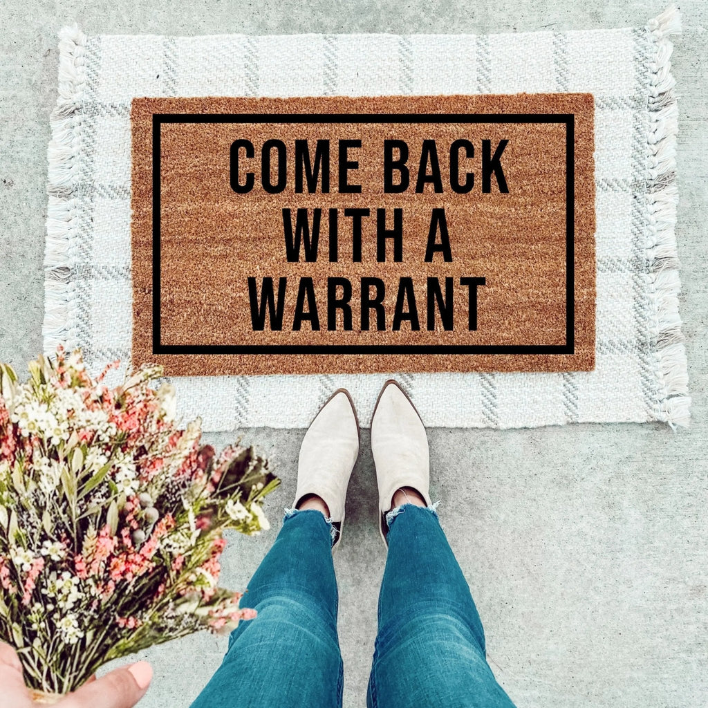 Come Back With A Warrant text on a natural brown coir doormat with black ink