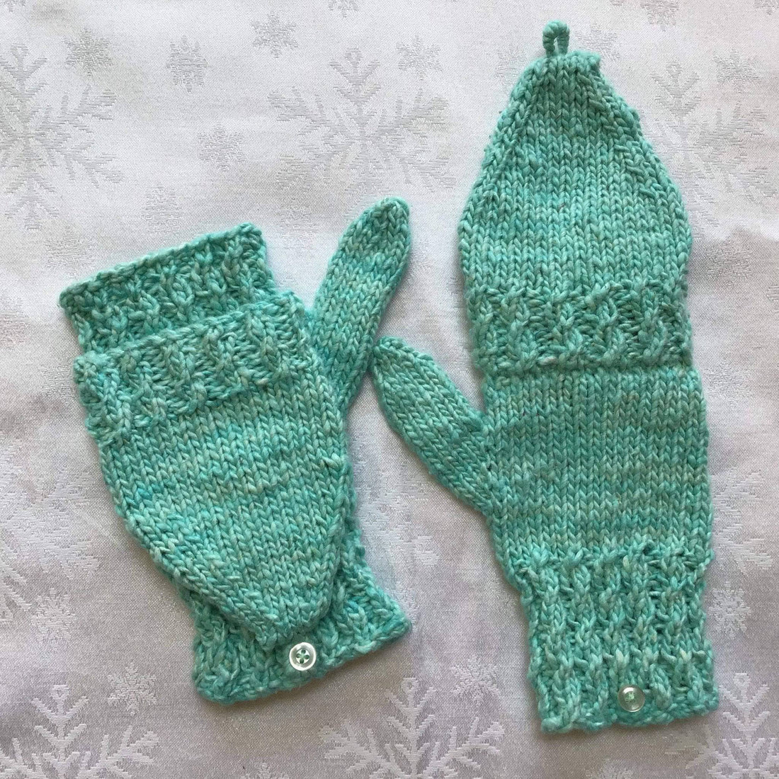 Hand-knitted convertible mittens featuring mock cable texture in a bright color.