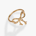 Polished gold-plated coquette bow ring featuring round-cut clear crystals on a white background.