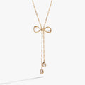 Gold-toned coquette bow necklace featuring clear geometric crystals and an adjustable slider mechanism