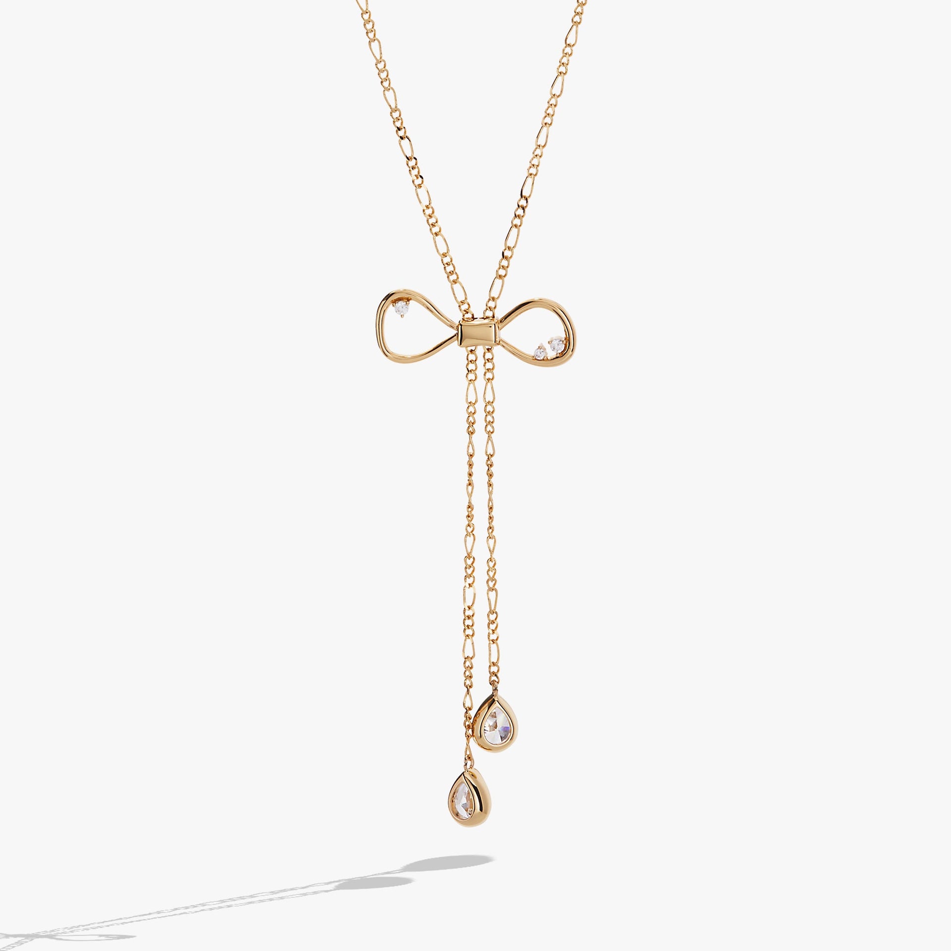 Gold-toned coquette bow necklace featuring clear geometric crystals and an adjustable slider mechanism
