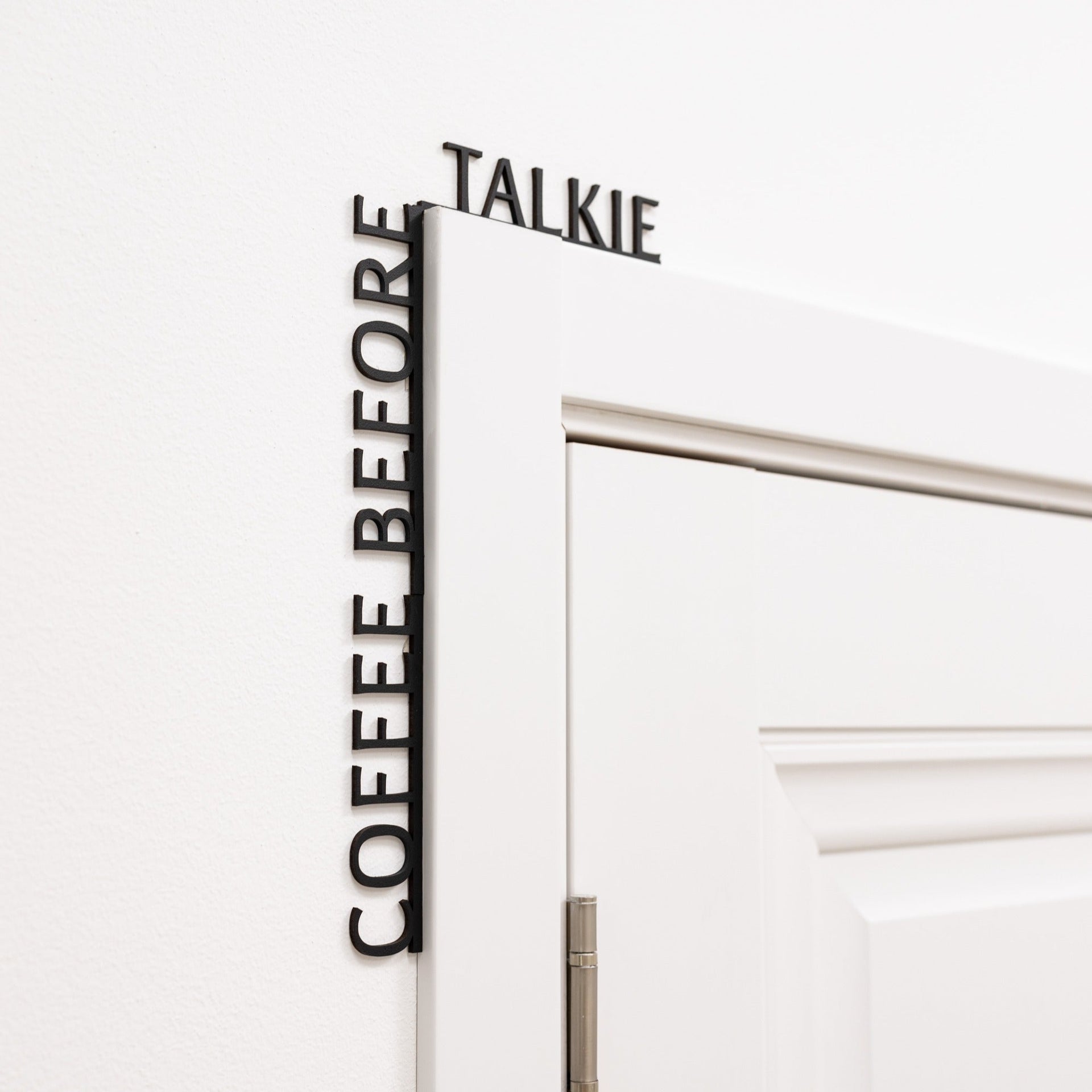 Minimalist black Coffee Before Talkie wooden corner quote installed in a kitchen.