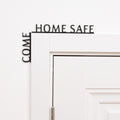 Minimalist black 'Come Home Safe' wooden quote displayed in a modern entryway corner.