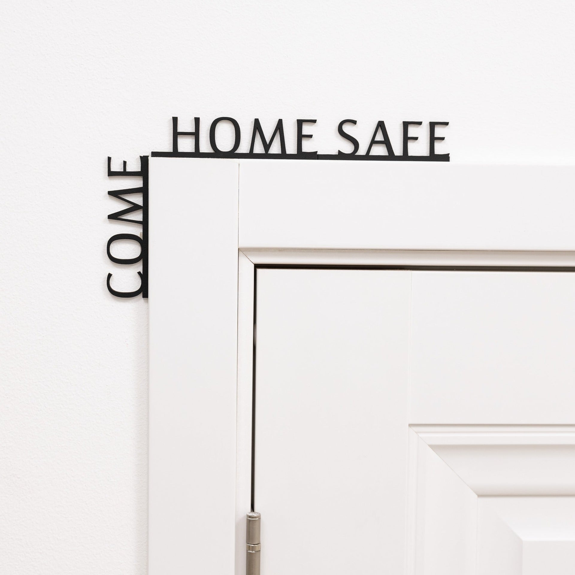 Minimalist black 'Come Home Safe' wooden quote displayed in a modern entryway corner.