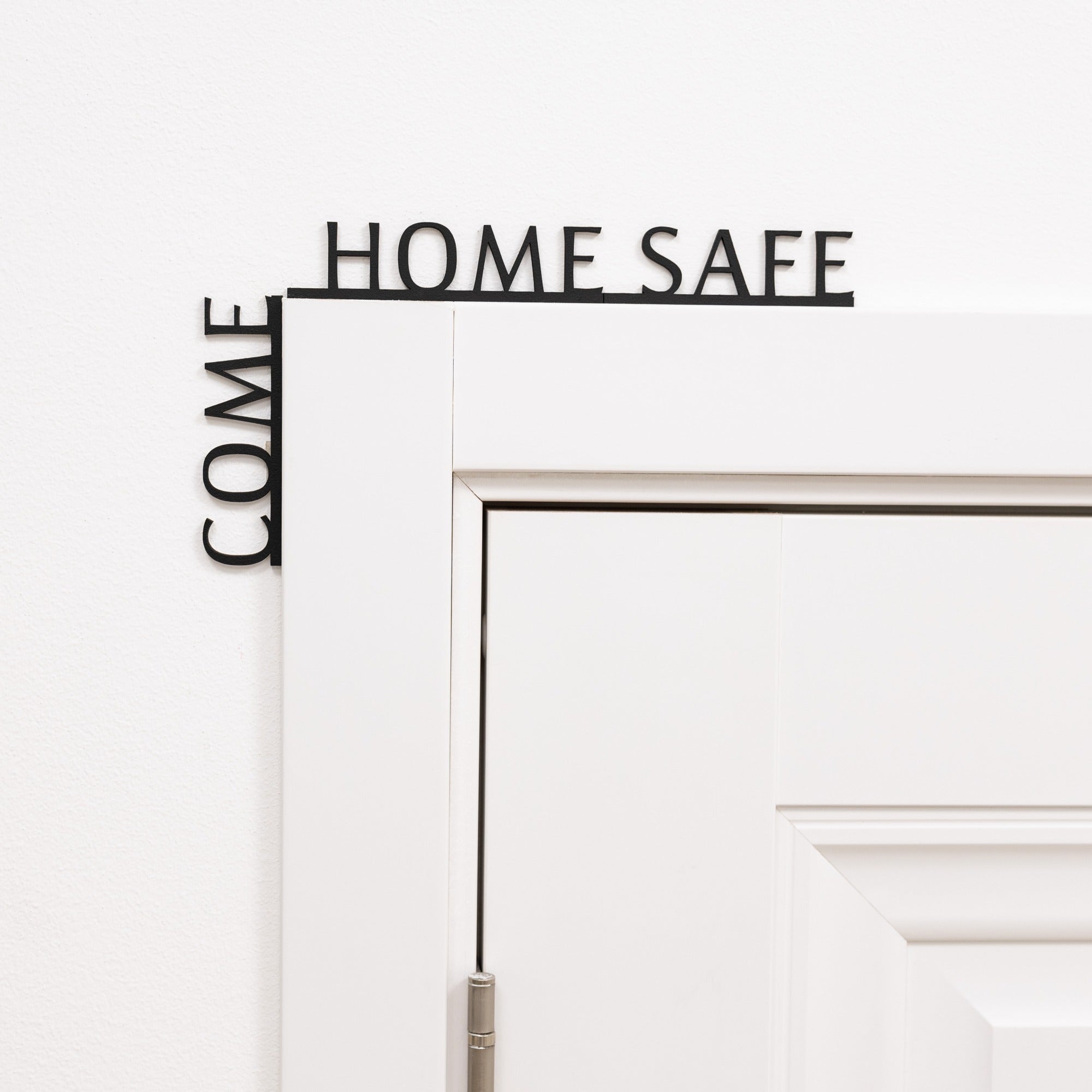 Minimalist black 'Come Home Safe' wooden quote displayed in a modern entryway corner.