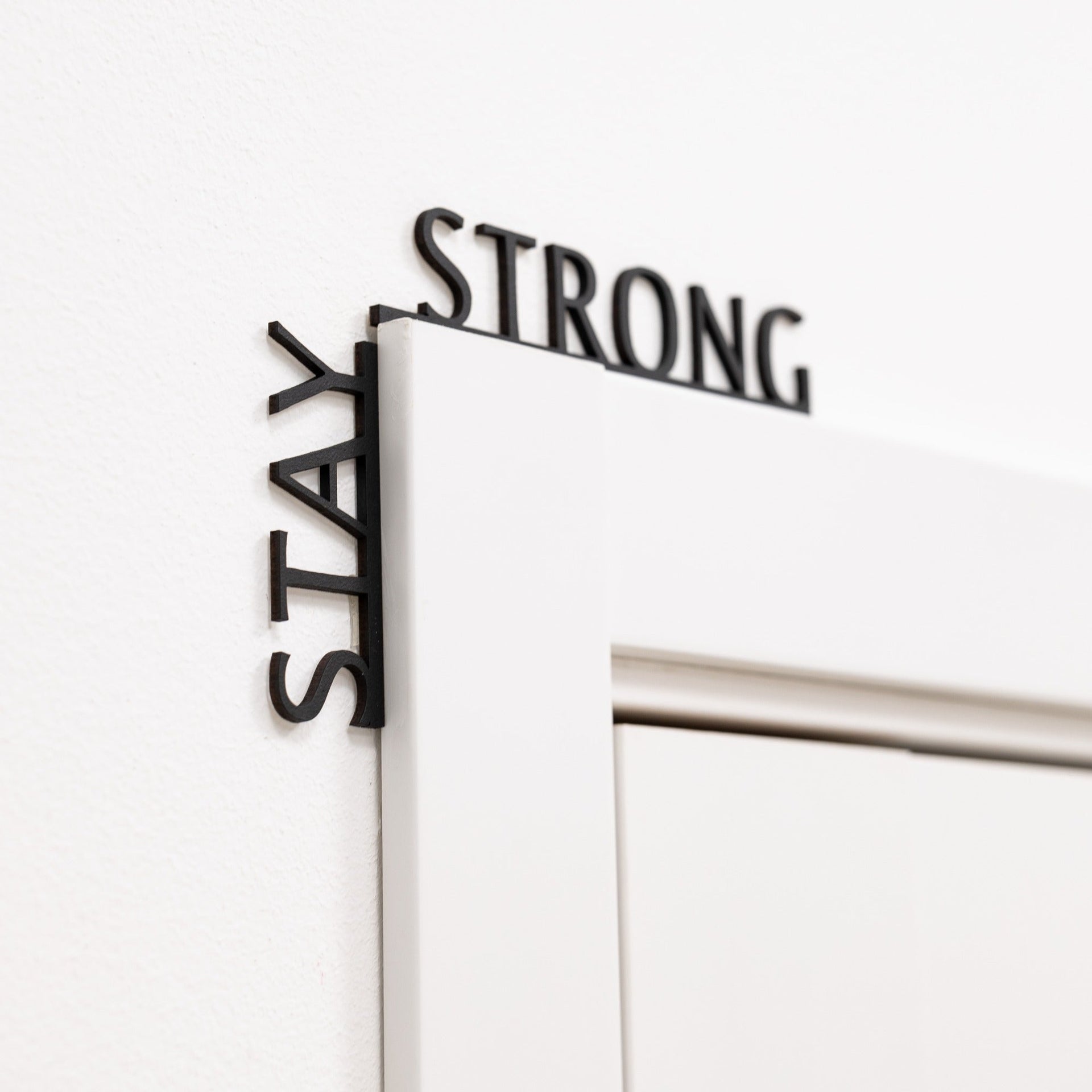 Minimalist black wooden wall art featuring the text Stay Strong.