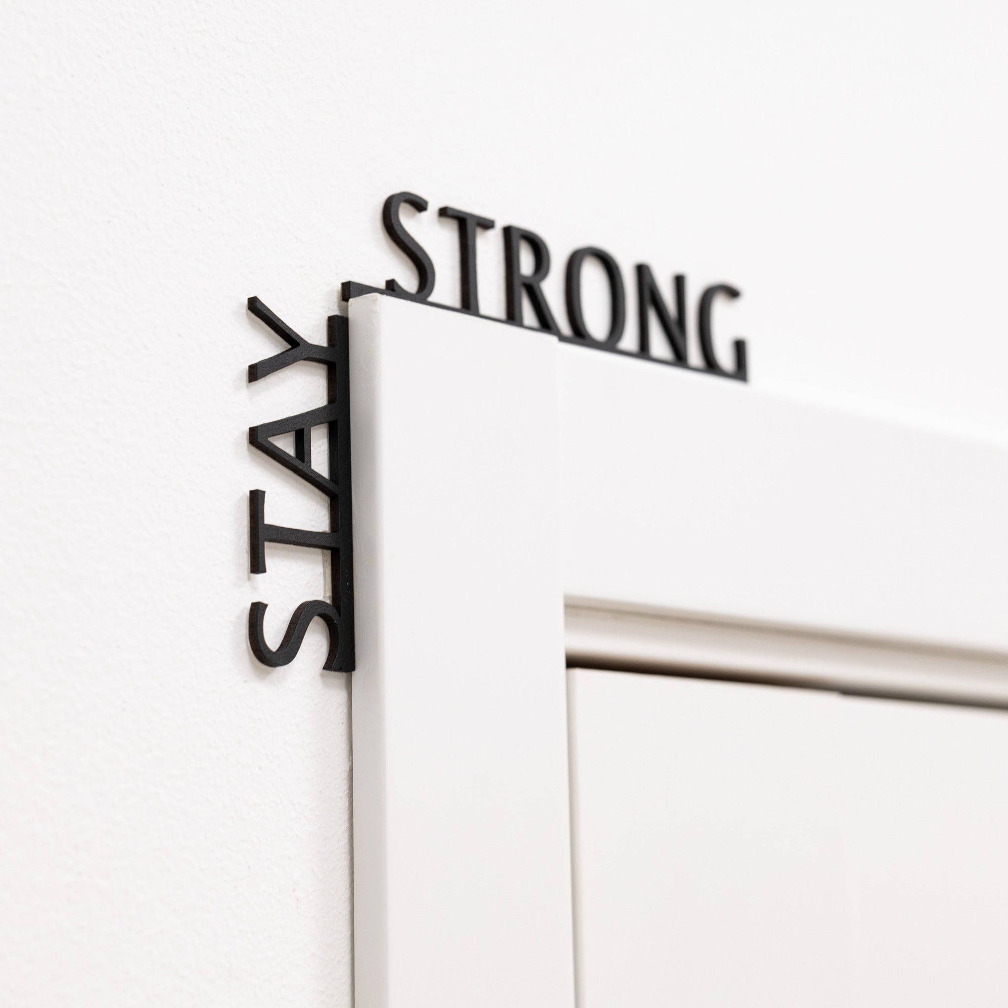 Minimalist black wooden wall art featuring the text Stay Strong.