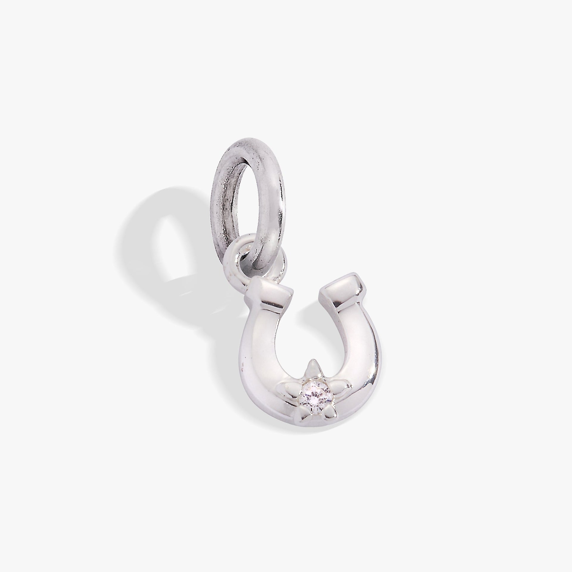 A close-up of a polished 925 sterling silver horseshoe charm with a single round clear crystal in a prong setting.