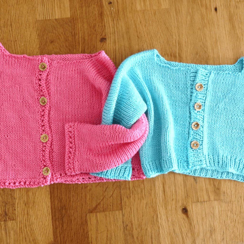 Close-up of a handmade bright pastel pink baby cardigan with button closure, styled for a classic casual look.