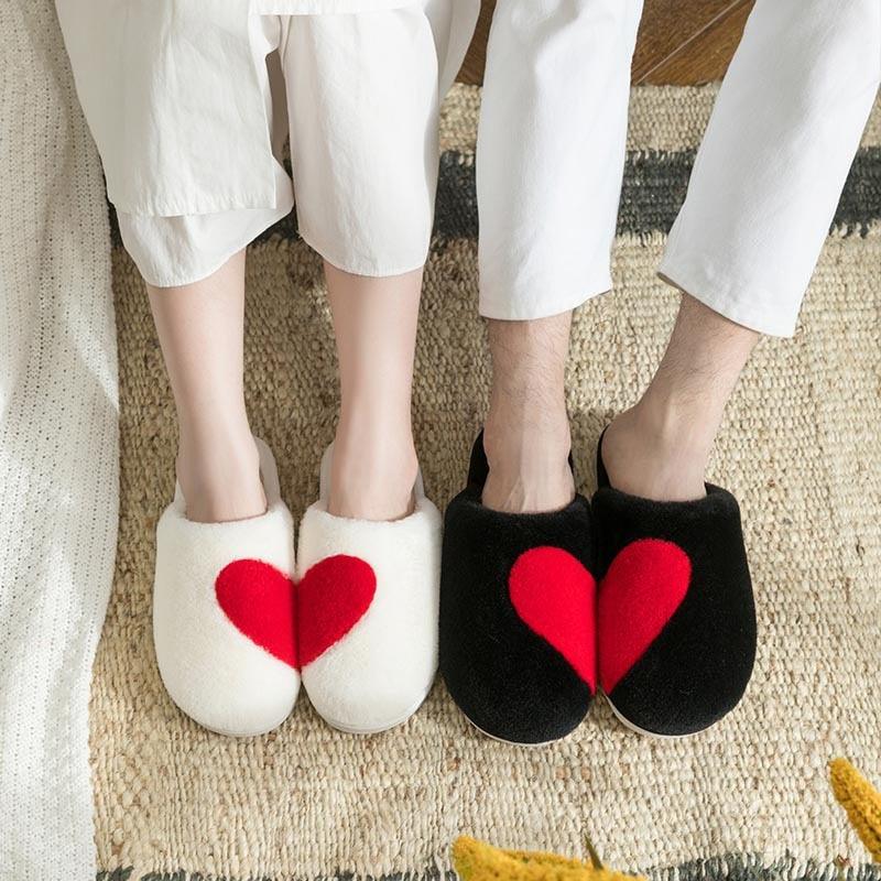 Women's black fuzzy house slippers with knit texture and horn button detail on a soft surface.