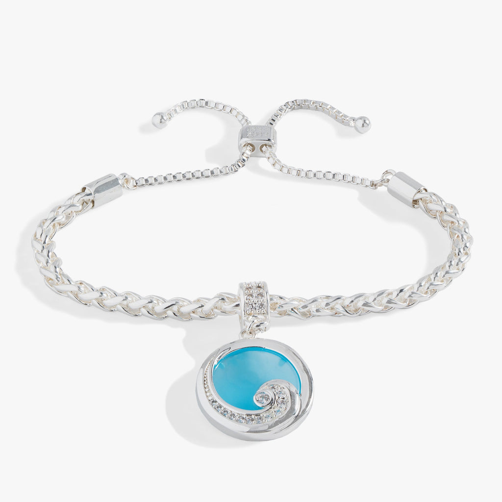 Silver bolo bracelet with a blue opal-colored charm and crystal-encrusted wave motif.
