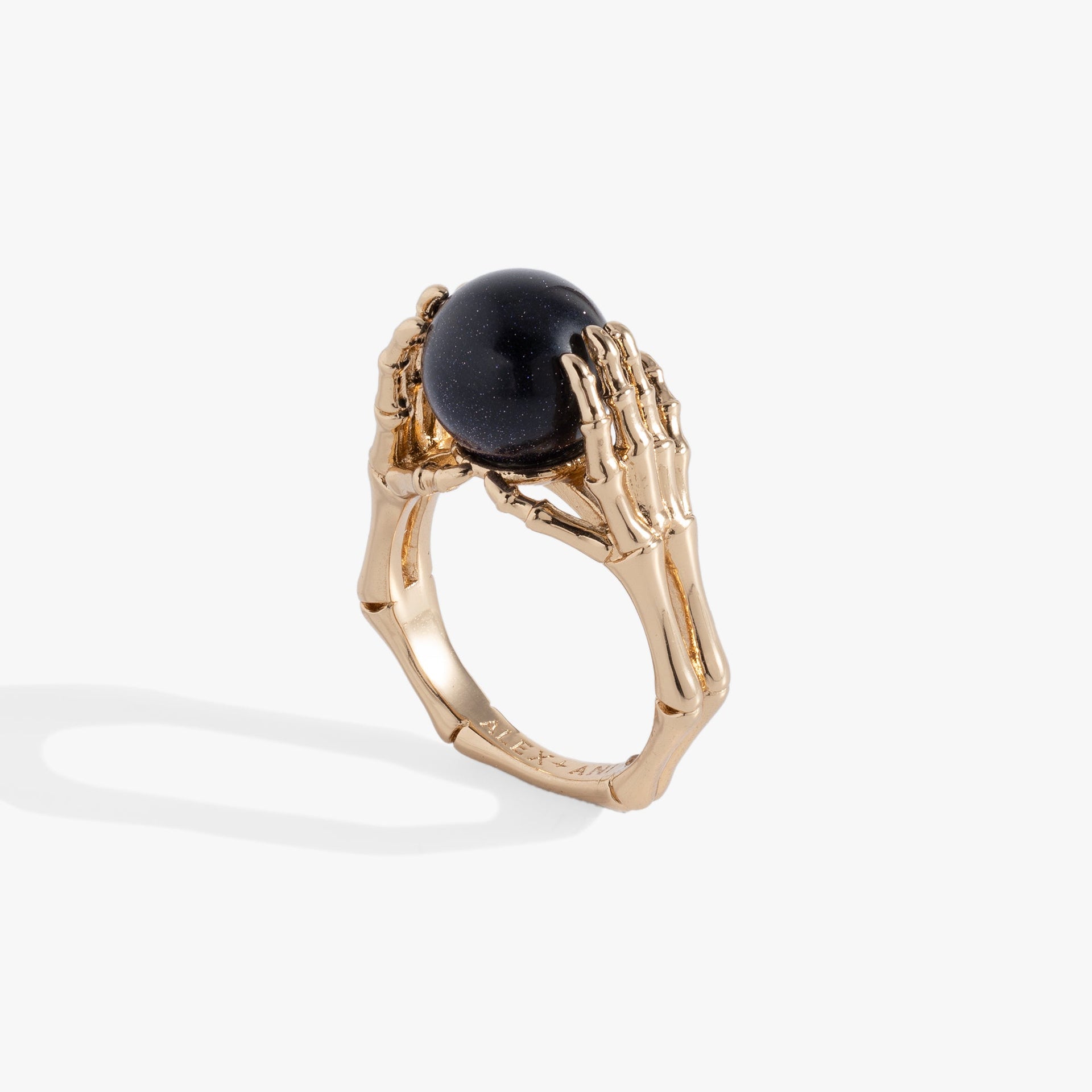 Close-up of a polished silver ring featuring detailed skeleton hands holding a round, deep navy-blue crystal ball.
