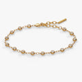 Close-up of a gold-tone cable chain bracelet with round clear crystals in bezel settings.
