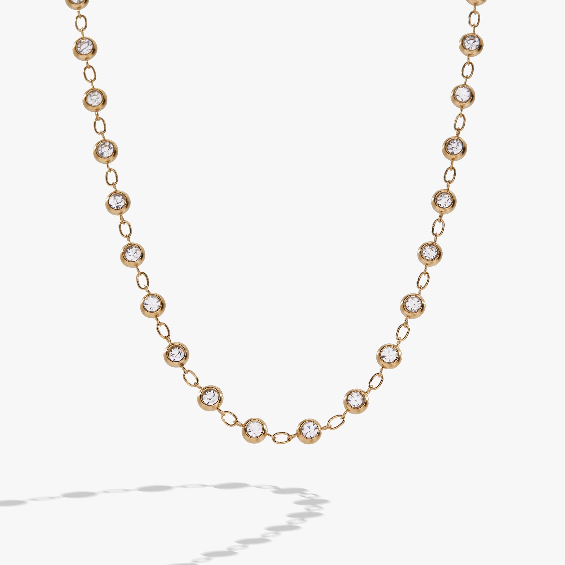Gold-tone chain necklace featuring alternating clear crystal pebbles and polished links.