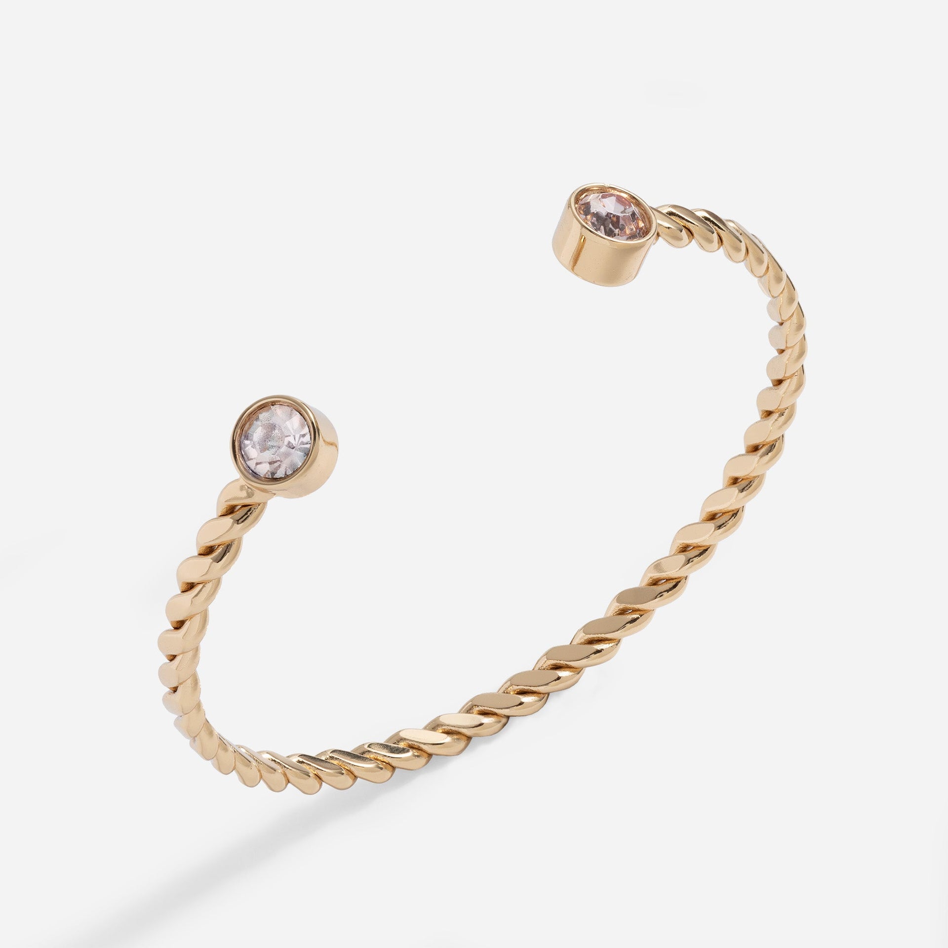 Twisted gold cuff bracelet with light-pink crystals at both ends.