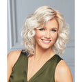 Woman wearing a collar-length Curl Up wig with spiral waves in platinum and ash blonde highlights