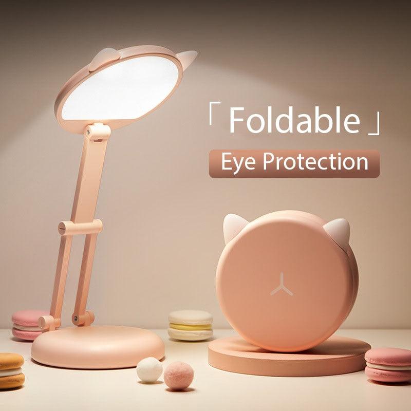 Cute pink cat-shaped LED desk lamp with foldable head on a child's study desk.