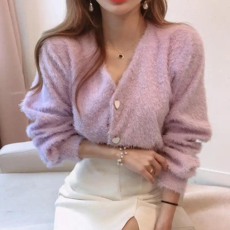 Woman wearing a lightweight V-neck button down knit cardigan with contrast detail.