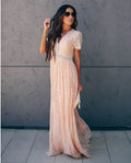 A woman wearing a peach-colored lace maxi dress with a V-neck and short sleeves.
