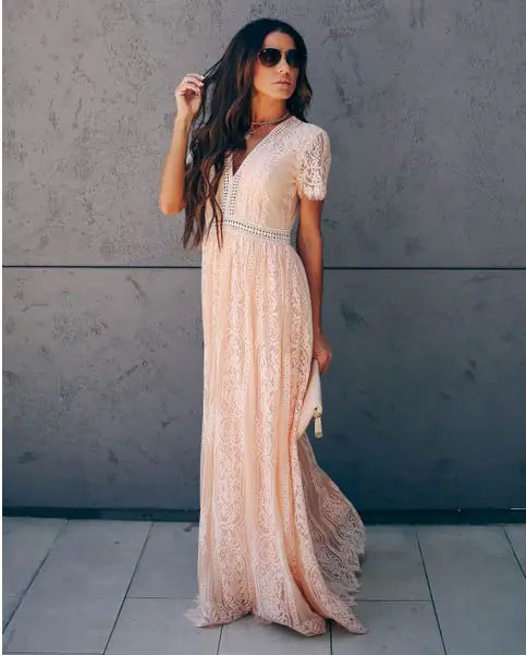 A woman wearing a peach-colored lace maxi dress with a V-neck and short sleeves.