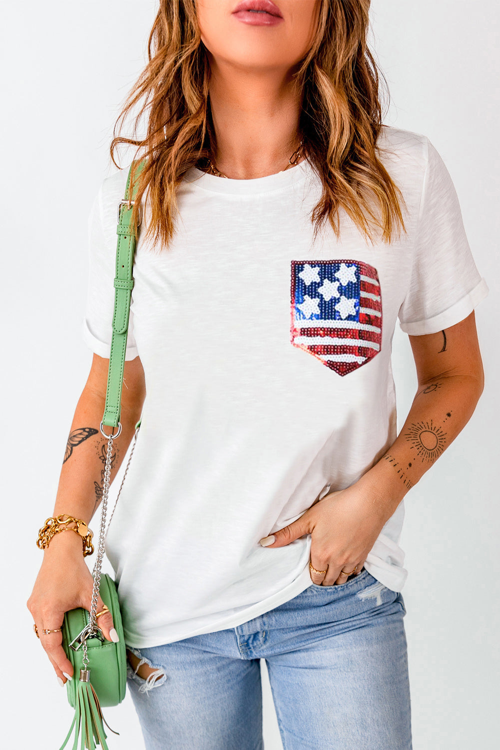A woman wearing a white round neck t-shirt with a sequin American flag design on the chest pocket