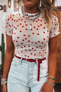 A stylish woman wearing a white mesh short sleeve top with an allover red heart print, layered under a denim vest.