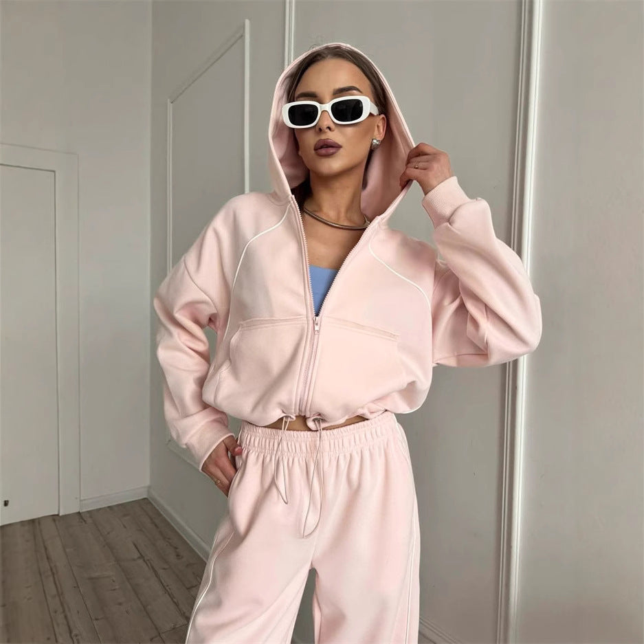 A woman wearing a solid color hooded zip-up jacket and matching jogger pants sportswear set.