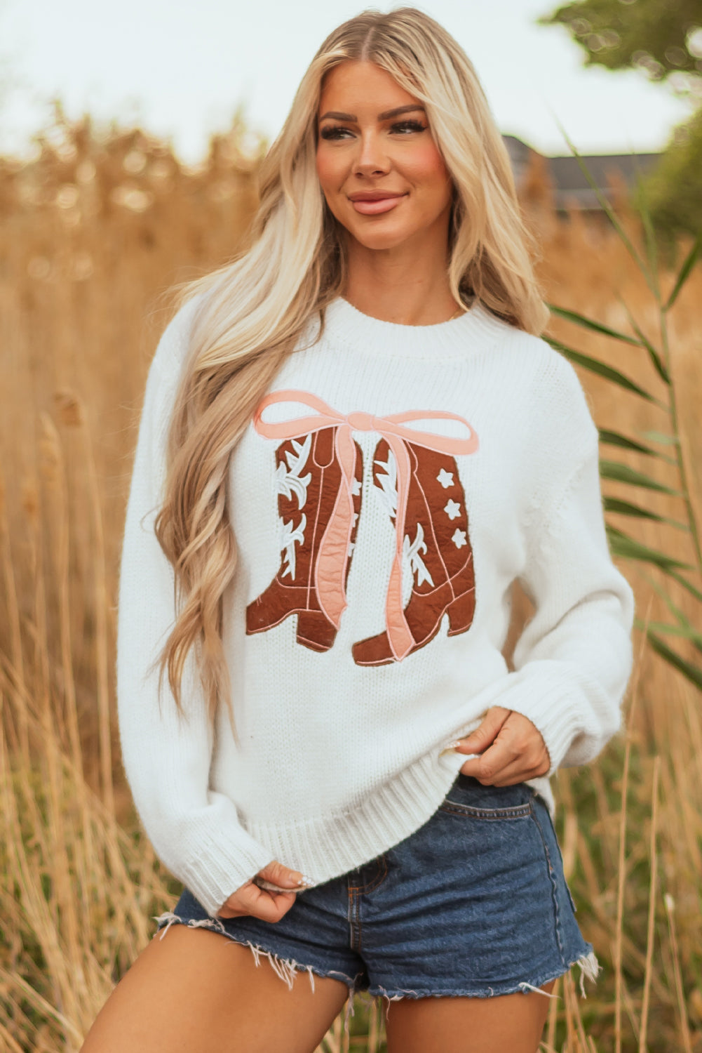 Woman wearing a cozy knit sweater with a western-style embroidered bow boots graphic