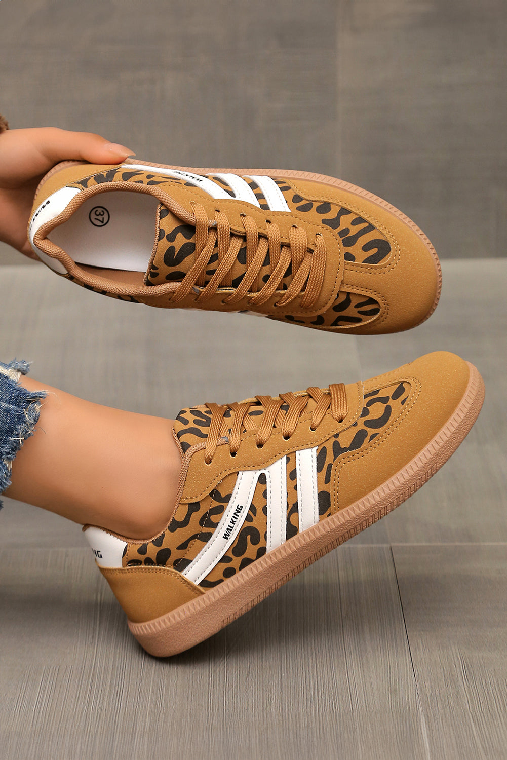 Close-up side view of a stylish brown leopard print lace-up sneaker with white stripe details and a rubber sole.