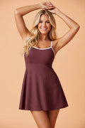 Woman wearing a knee-length, deep burgundy and white colorblock ribbed swim dress with a scoop neck and side pockets.