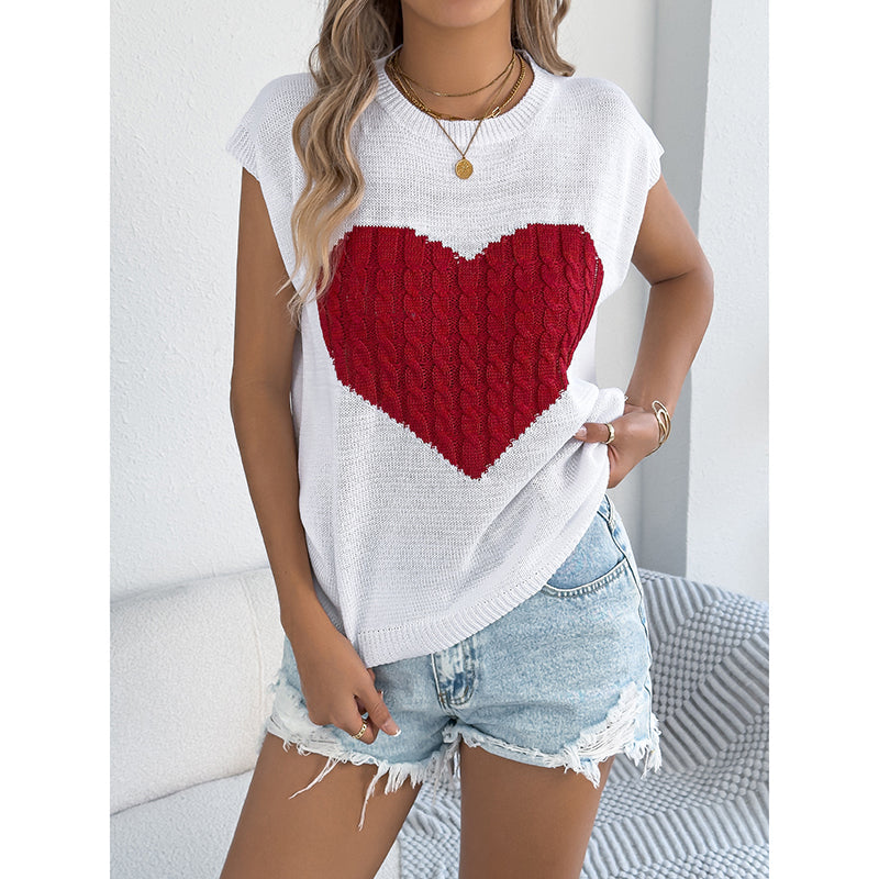 Model wearing a white sleeveless knit tank top featuring a large red cable-knit heart design.