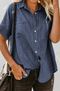 A woman wearing a blue short-sleeve denim button-up shirt with a chest pocket and a curved hem.
