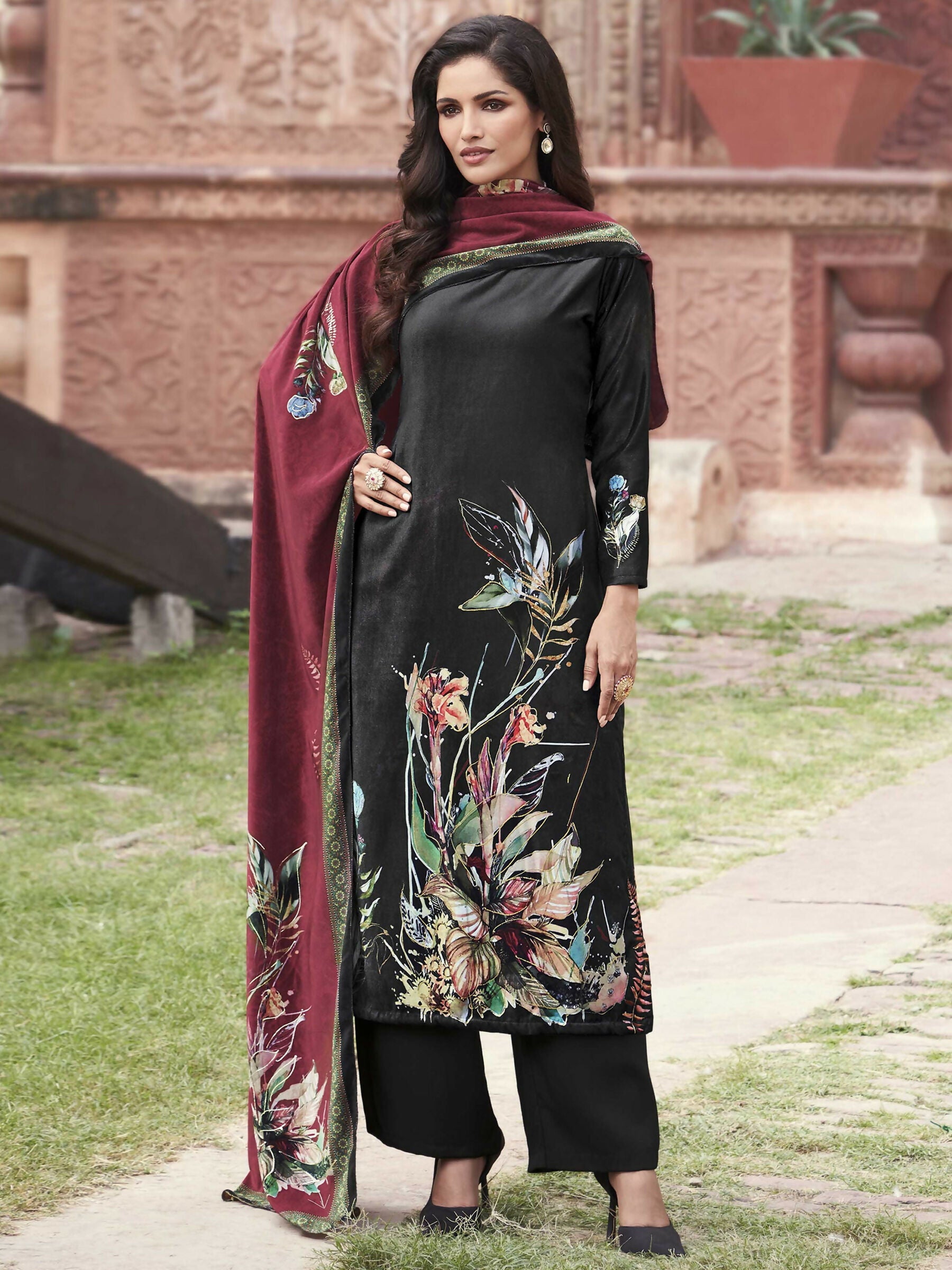 Woman wearing a black velvet straight kurta set with vibrant floral digital print and matching dupatta.