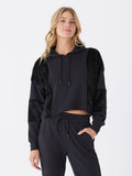 A close-up of a women's black sherpa and fleece pullover hoodie showing the texture and hood detail.