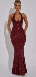 A woman wearing a fitted burgundy sequin halter maxi dress
