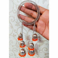 Close up of vibrant orange pearl bangles with hanging silver-tone dangles