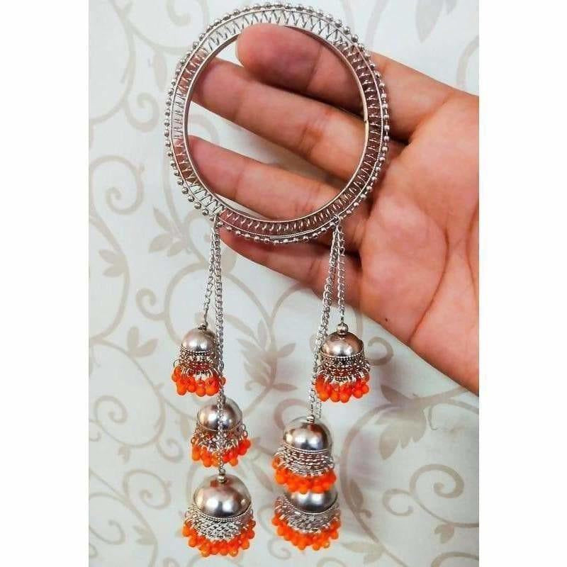 Close up of vibrant orange pearl bangles with hanging silver-tone dangles