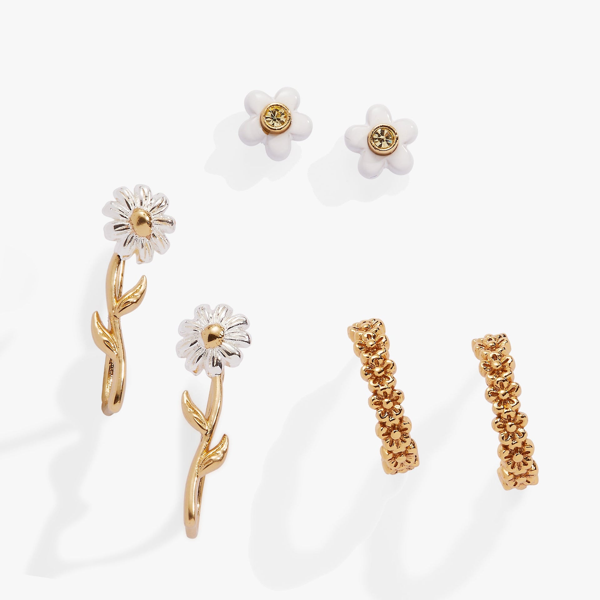 A 3-piece jewelry set featuring daisy-themed stud earrings, huggie hoops, and an ear climber in gold and white tones.