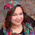 A woman wearing a vibrant, multi-colored ripple slouch hat with a bohemian aesthetic.