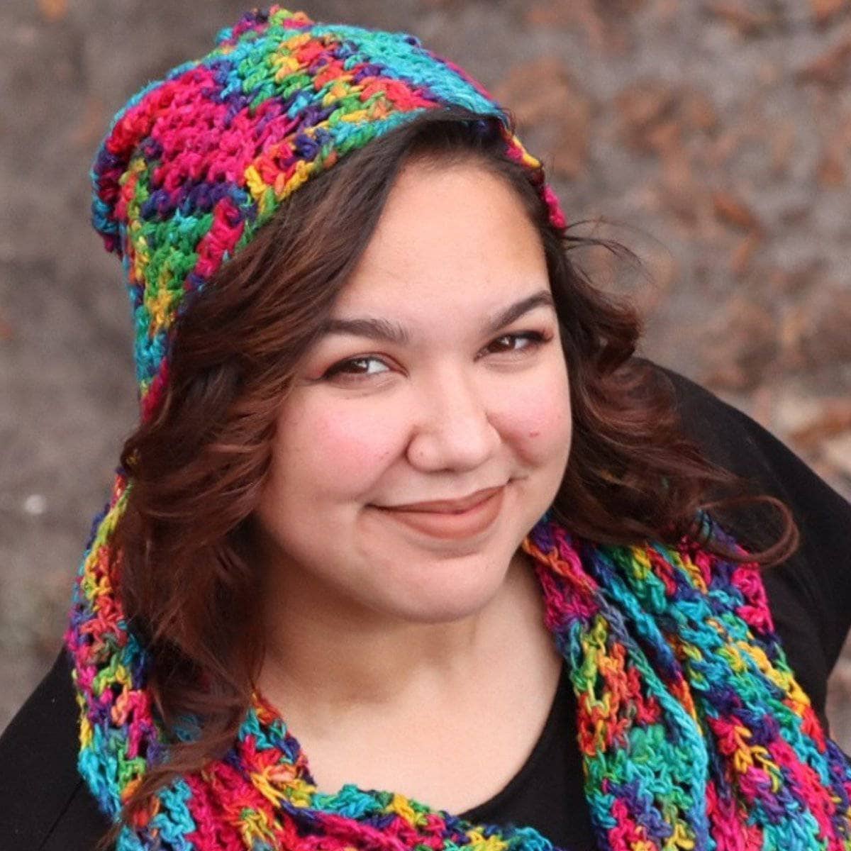 A woman wearing a vibrant, multi-colored ripple slouch hat with a bohemian aesthetic.