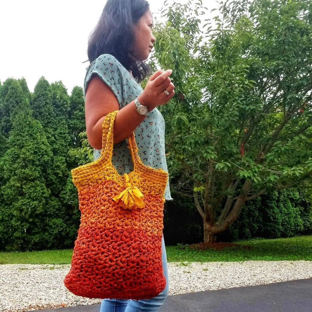 Darn Good Tote Bag kit featuring skeins of yellow, orange, and red yarn