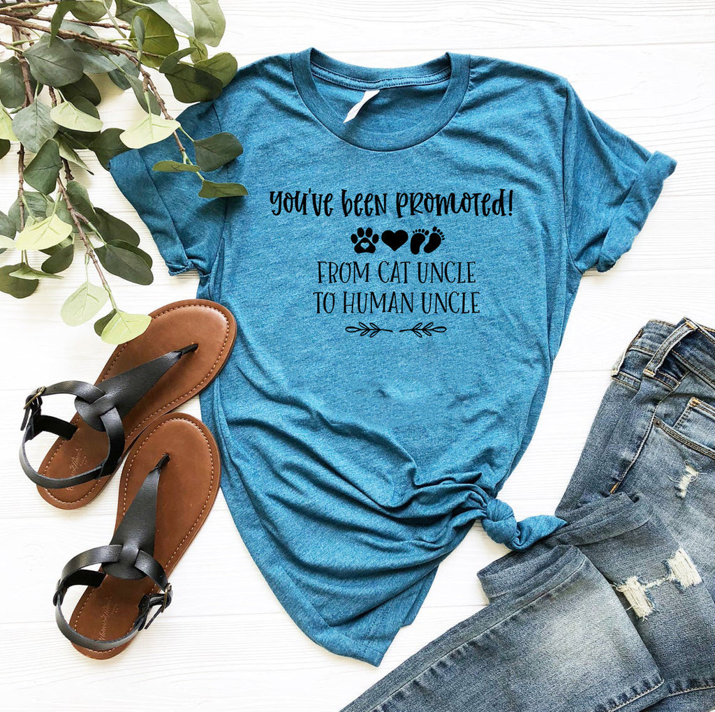 Blue t-shirt with graphic print reading You've been promoted from cat uncle to human uncle