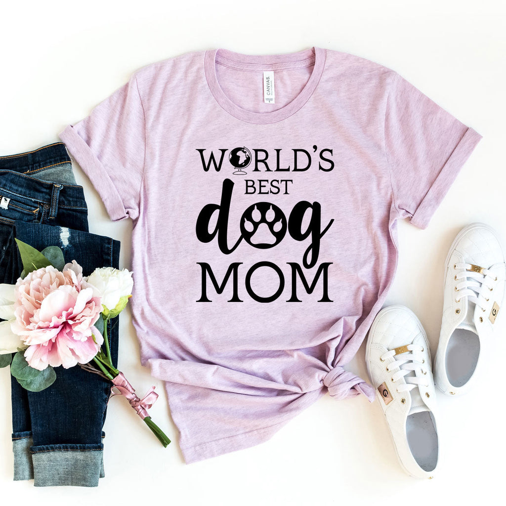 A lavender short-sleeve t-shirt with 'World's Best Dog Mom' printed in black text, styled on a white background with jeans and sneakers.