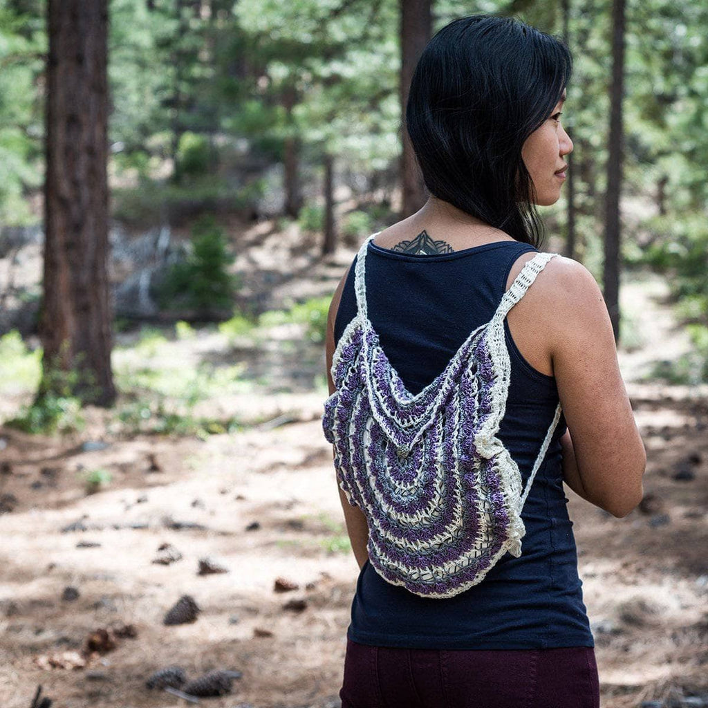 Close-up of a handmade crochet bag featuring a colorful mandala design with adjustable strap knots.