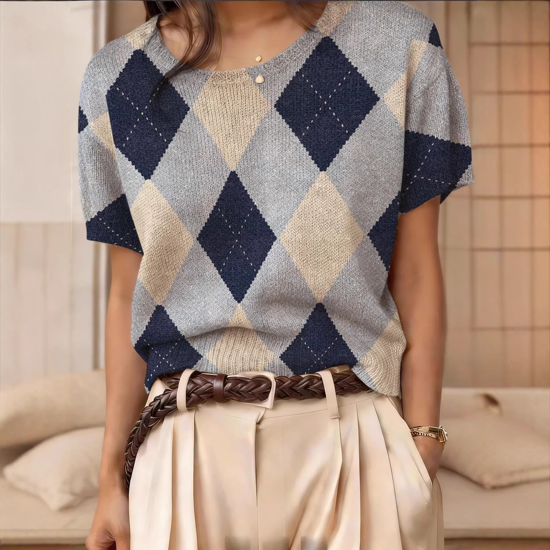 A woman wearing a short-sleeve argyle pattern knit top with a scoop neckline and ribbed hem.