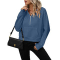 A woman wearing a blue half zip hooded pullover sweatshirt with a kangaroo pocket.