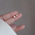 Minimalist gold-plated heart stud earrings on a neutral background