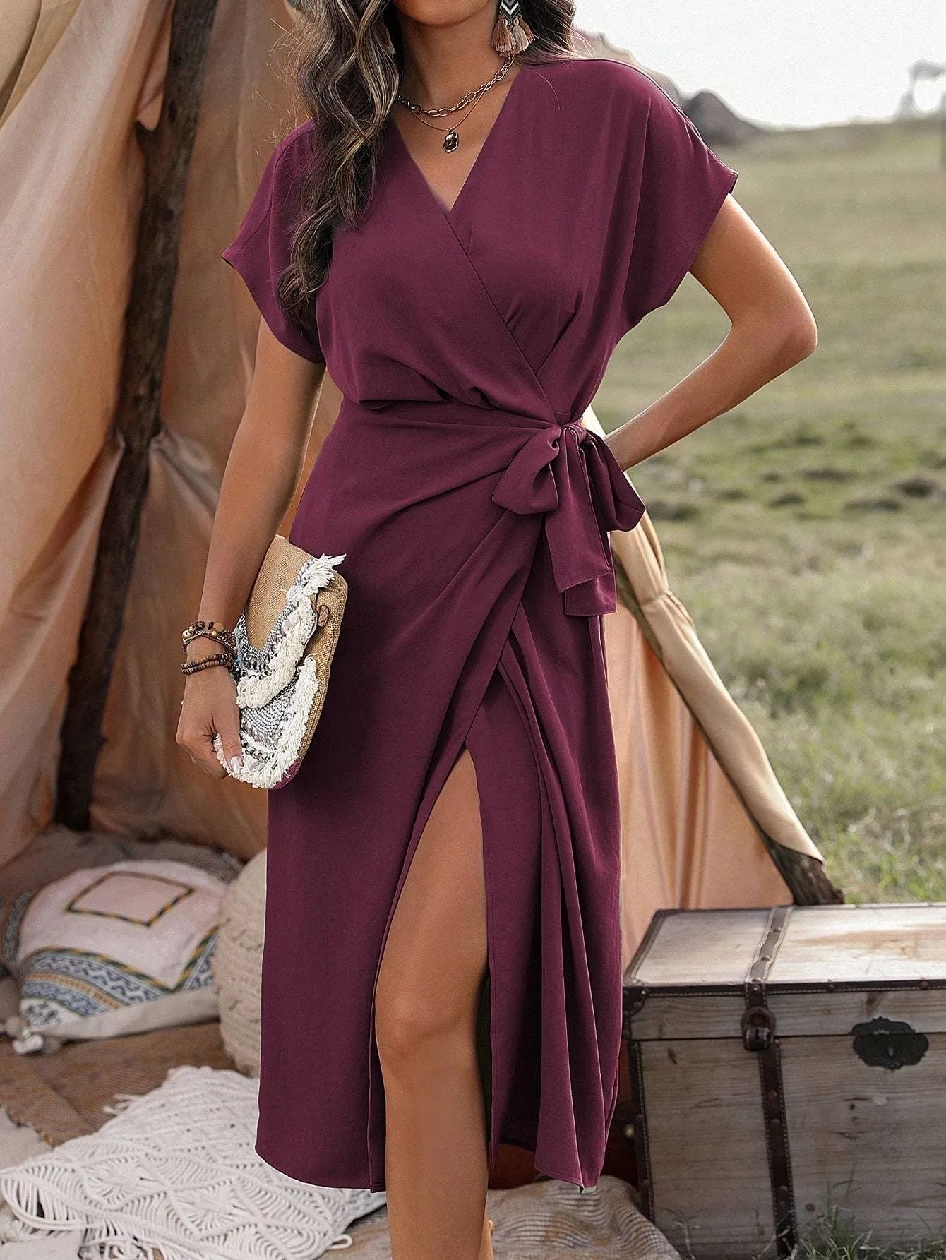 Woman wearing a solid color asymmetric wrap suspender dress in a minimalist style